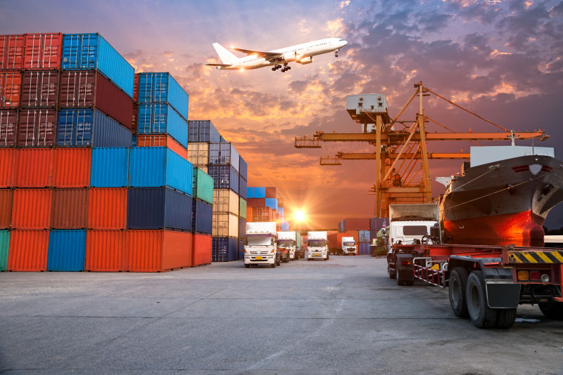 集装箱货物运输的物流进出口图片-有货运飞机飞过的天空下的集装箱货物
